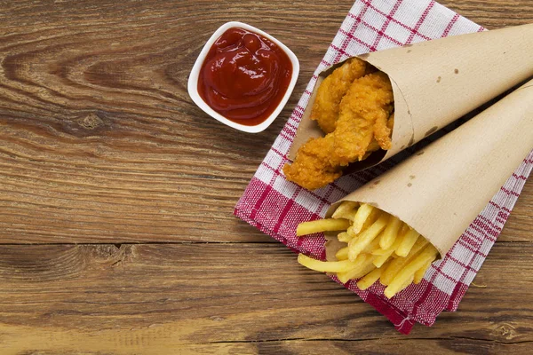 Nuggets y papas fritas servidas en una bolsa de papel con un baño — Foto de Stock