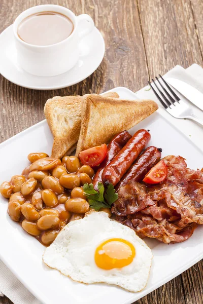 Полный английский завтрак с беконом, соусом, жареным яйцом, запеченной фасолью — стоковое фото
