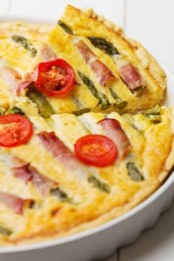 Kuşkonmazlı tart ve beyaz ahşap arka planda domates..