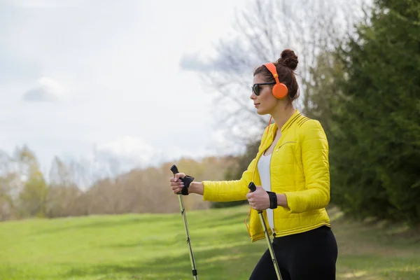 Frau in gelber Jacke und schwarzer Leggings beim Nordic Walking — Stockfoto