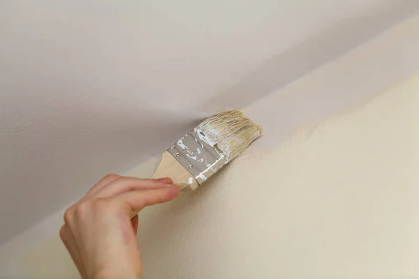 Pinsel schweißt die Wände mit weißer Farbe von der Decke. — Stockfoto