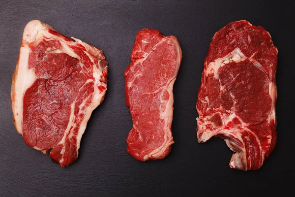 Steak de bœuf cru frais sur un plateau en pierre noire — Photo