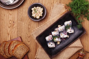 Sirke de haddelenmiş ringa, soğan ve turşu ile servis. 