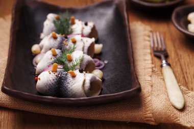 Sirke de haddelenmiş ringa, soğan ve turşu ile servis. 