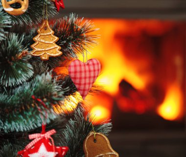 Noel süsleri ağaca asılmış. Alevli şömine