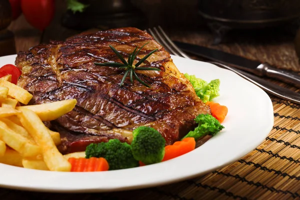 Bife grelhado servido com batatas fritas e legumes em um — Fotografia de Stock