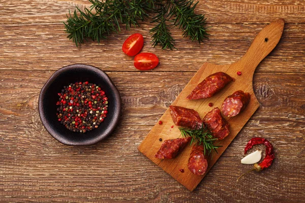 Köstliche Räucherwurst, in Scheiben geschnitten auf einem Holzbrett mit Gewürzen. — Stockfoto