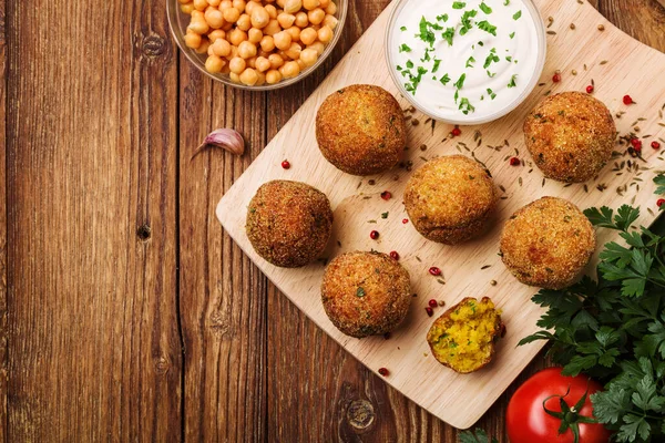 Mingi de falafel de năut pe un birou din lemn cu legume — Fotografie, imagine de stoc