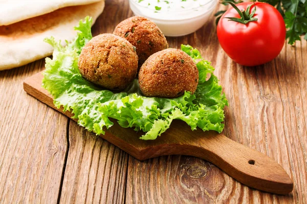 Bolinhas de falafel de grão de bico em uma mesa de madeira com legumes — Fotografia de Stock