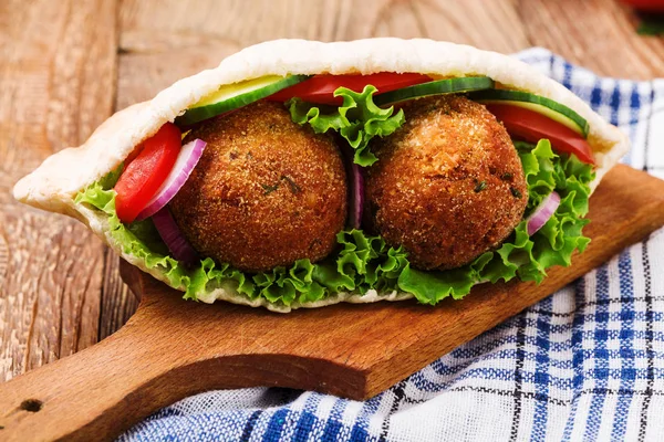 Falafel e legumes frescos em pão de pita na mesa de madeira — Fotografia de Stock