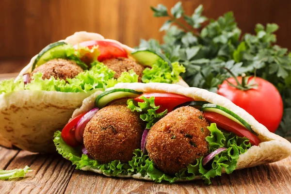 Falafel en verse groenten in pitabrood op houten tafel — Stockfoto