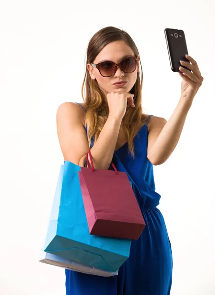 Young woman in a blue suit, with colorful shopping bags doing se — Stock Photo, Image