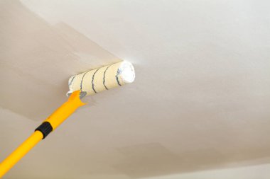 Tavanı beyaz boya ile bir rulo boyama.