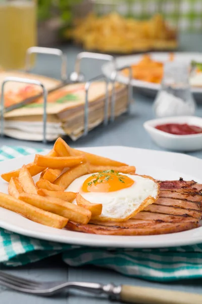 Englisches Frühstück mit gegrilltem Schinken, Spiegelei und Pommes. — Stockfoto