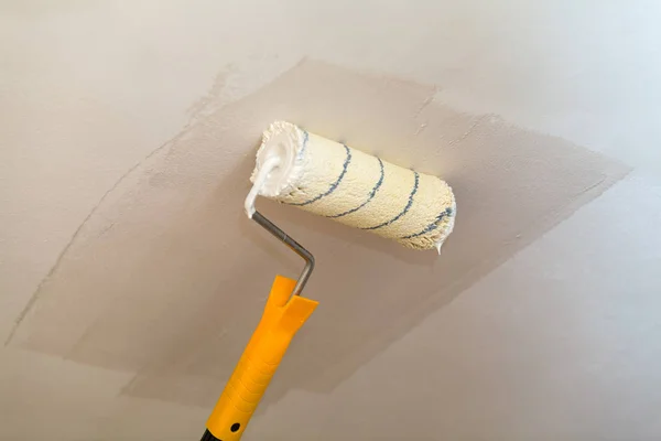 Pintura del techo un rodillo con pintura blanca . — Foto de Stock