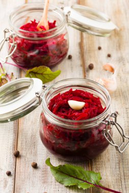 Kavanozda marine edilmiş rendelenmiş pancar kökü. Ahşap arkaplan.