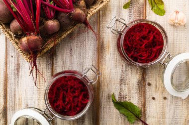 Kavanozda marine edilmiş rendelenmiş pancar kökü. Ahşap arkaplan.