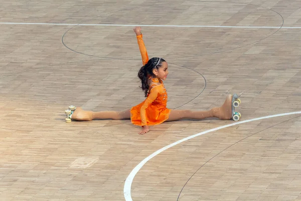 Turuncu elbiseyle artistik patinajda güzel bir kız.