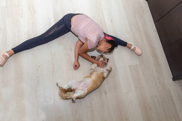 Aerial shot of teenager pampering her pet in her living room while practicing ballet, dance, yoga, gymnastics