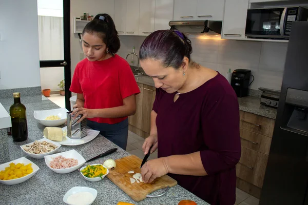 Bir anne ve kızı evlerinin mutfağında yemek hazırlıyorlar.