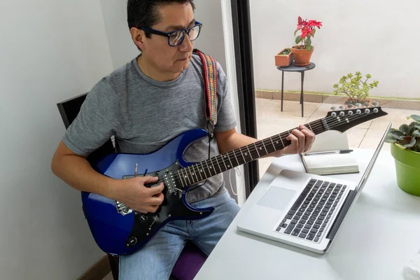 Karantina sırasında evdeki bir odada gitar dersi alan bir adamın portresi