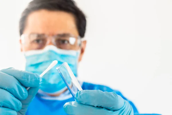 Coronavirus muayenesi için test tüpü ve burun örneği olan bir doktorun elleri.