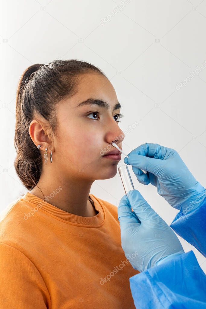 Hands of medical personnel taking a nasal sample for medical examination of coronavirus from a teenage girl