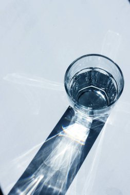 Beyaz arka planda güçlü gölgeleri olan su bardağı, 2020 'de klasik mavi tonda.