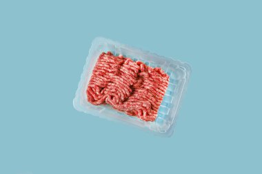 Kıyma ya da yapay et labaratuvarın mavi arka planında izole edilmiş. Bitki bazlı ve temiz protein konsepti. Biyoteknolojinin gelecekteki gıda eğilimi 