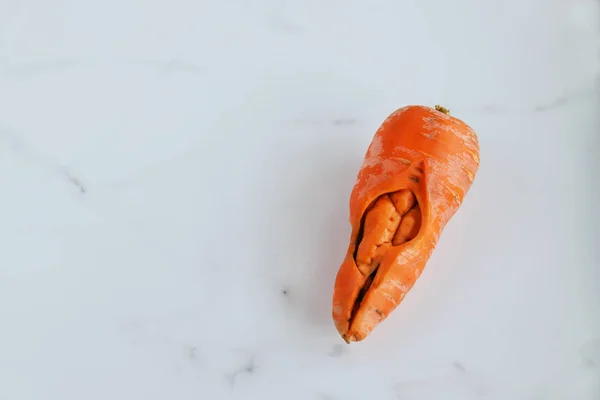 丑陋的胡萝卜流行的食物浪费概念与复制空间 灰色大理石背景上有趣的怪物蔬菜 顶视图 — 图库照片