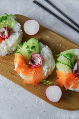 Taze sebzeli Asya yemeği suşi çörekleri. Vejetaryenler ve vejetaryenler için çağdaş atıştırmalıklar. Pirinç, havuç, salatalık ve simit şeklinde turp.