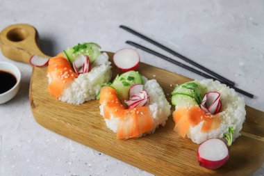 Taze sebzeli Asya yemeği suşi çörekleri. Vejetaryenler ve vejetaryenler için çağdaş atıştırmalıklar. Pirinç, havuç, salatalık ve simit şeklinde turp.