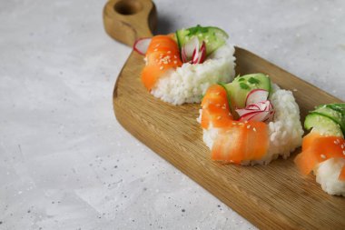 Taze sebzeli Asya yemeği suşi çörekleri. Vejetaryenler ve vejetaryenler için çağdaş atıştırmalıklar. Pirinç, havuç, salatalık ve simit şeklinde turp.