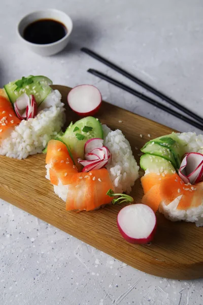 Taze sebzeli Asya yemeği suşi çörekleri. Vejetaryenler ve vejetaryenler için çağdaş atıştırmalıklar. Pirinç, havuç, salatalık ve simit şeklinde turp.
