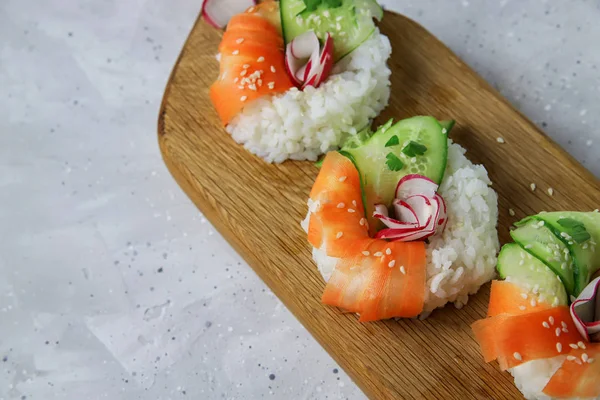 Taze sebzeli Asya yemeği suşi çörekleri. Vejetaryenler ve vejetaryenler için çağdaş atıştırmalıklar. Pirinç, havuç, salatalık ve simit şeklinde turp.