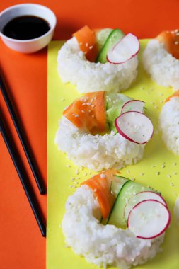 Çiğ havuçlu, salatalıklı ve turplu suşi çörekleri. Çağdaş gıda konsepti, vejetaryen ya da vejetaryen için modaya uygun Asya yemeği, yakın plan, üst görünüm