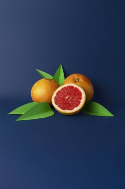 Juicy grapefruits with green leaves from paper on blue background. Creative summer composition. Citrus still life