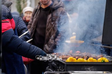 Izgarada barbekü, aromatik dumanın içinde. İştah açıcı sıcak et parçaları şiş kömürde kızartılıyor..