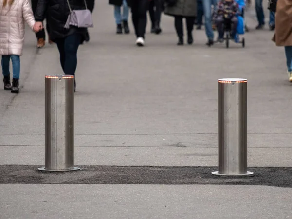 Automatische zylindrische Barrieren in der Fußgängerzone vor dem Hintergrund verschwommener Füße von Fußgängern. — Stockfoto