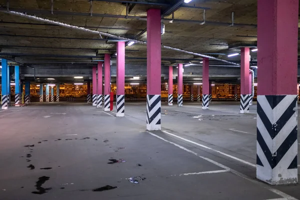 Columns in an empty underground parking at night in the light of artificial lighting. City infrastructure.