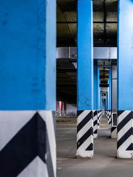 Columns in an empty underground parking at night in the light of artificial lighting. City infrastructure.