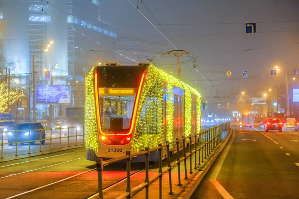 Moskau, Russland. 26. Dezember 2019: In einer nebligen Nacht fährt eine mit LEDs beleuchtete Straßenbahn auf Schienen. umweltfreundlicher öffentlicher Verkehr, geschmückt zu Ehren der Neujahrsfeiertage. — Stockfoto