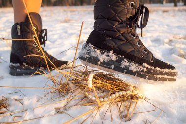 Kışın giydiği siyah botun içinde bir ayak inci mücevherlerin üzerinde kar asılı duruyor..