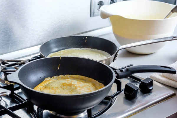 Дві сковороди для смаження на газовій плиті, в якій випікаються ароматні смачні млинці. Домашня кухня . — стокове фото