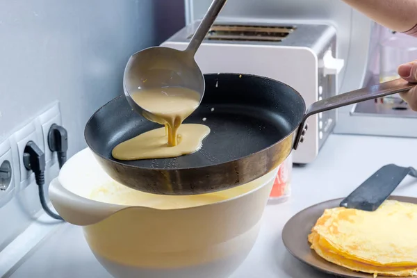 Баттер виливається з металевого відра на змащену сковороду. Процес випічки млинців . — стокове фото
