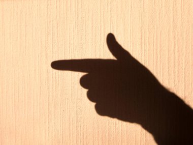 Parlak ışıkla aydınlatılmış sarı bir duvardaki insan avucunun gölgesi. Parmaklarla hareket et.