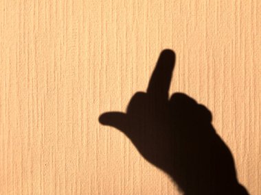 Sarı, parlak bir duvarda insan elinin gölgesi var. Orta parmağınla yaptığın müstehcen bir jest..