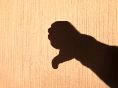 Parlak ışıkla aydınlatılmış sarı bir duvardaki insan avucunun gölgesi. Parmaklarla hareket et.