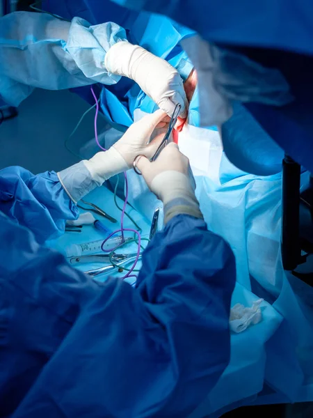 Manos ensangrentadas de cirujanos con guantes de látex estériles con instrumentos quirúrgicos con rastros de sangre. Cirugía . — Foto de Stock