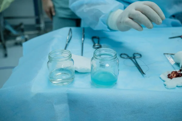 Sterile surgical instruments and glass containers with solutions on the table during a surgical operation.